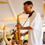 Saxophonist performing above a cheering lunch crowd at Nikki Beach Saint Barth