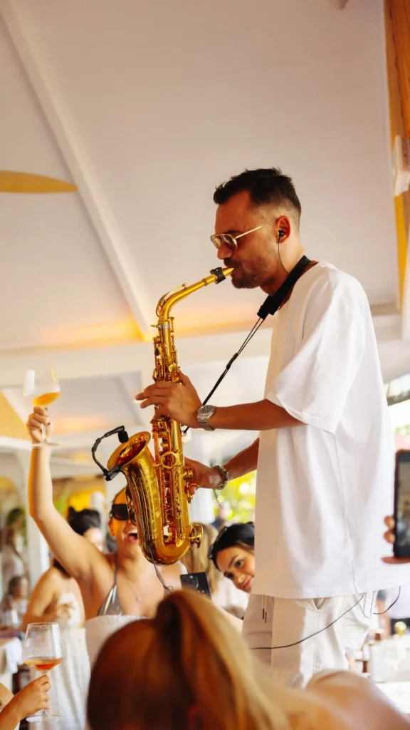 Saxophonist performing above a cheering lunch crowd at Nikki Beach Saint Barth