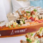 Sushi and sashimi assortment served on a branded wooden boat platter at Nikki Beach Saint Barth