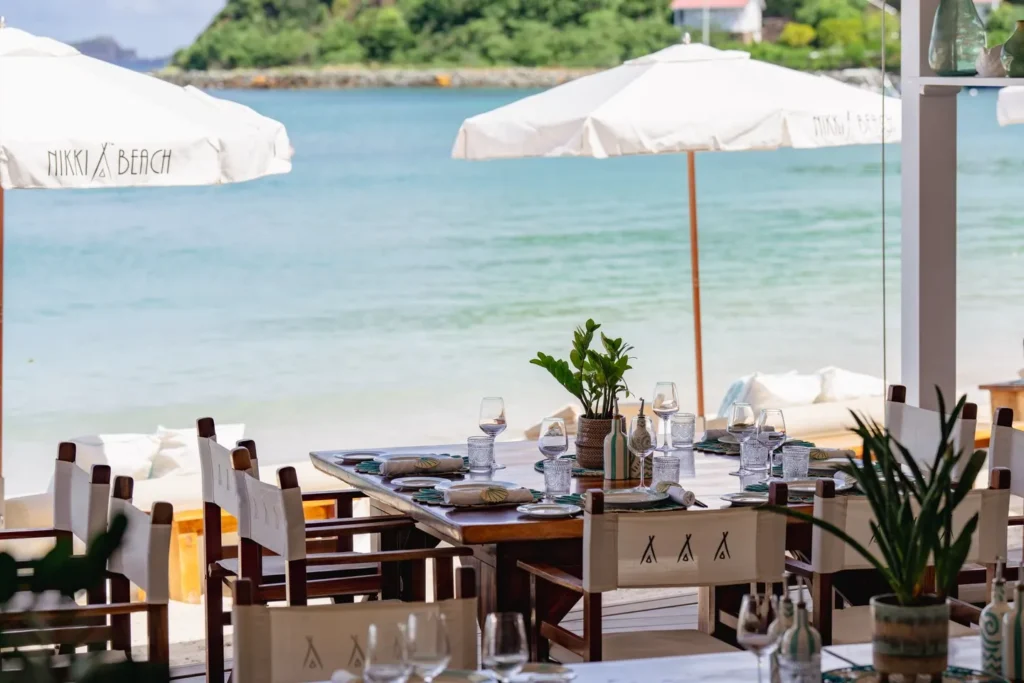 Set table under Nikki Beach parasols overlooking the turquoise bay at Nikki Beach Saint Barth