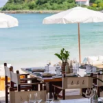 Set table under Nikki Beach parasols overlooking the turquoise bay at Nikki Beach Saint Barth