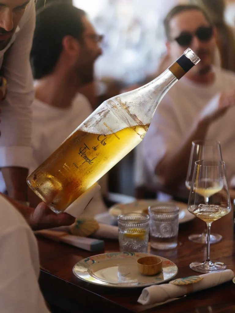 Server presenting a chilled bottle of rosé at a lunch table at Nikki Beach Saint Barth