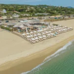 Aerial view of the beach club with sunbeds and the La Serena sign on the shore at Plage La Serena Ramatuelle Saint-Tropez