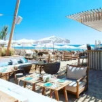 Beach lounge with low sofas, set tables and parasols on the sand at Plage La Serena Ramatuelle Saint-Tropez