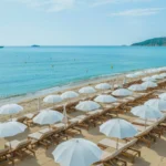 Rows of white parasols and sunbeds facing the turquoise sea at Plage La Serena Ramatuelle Saint-Tropez