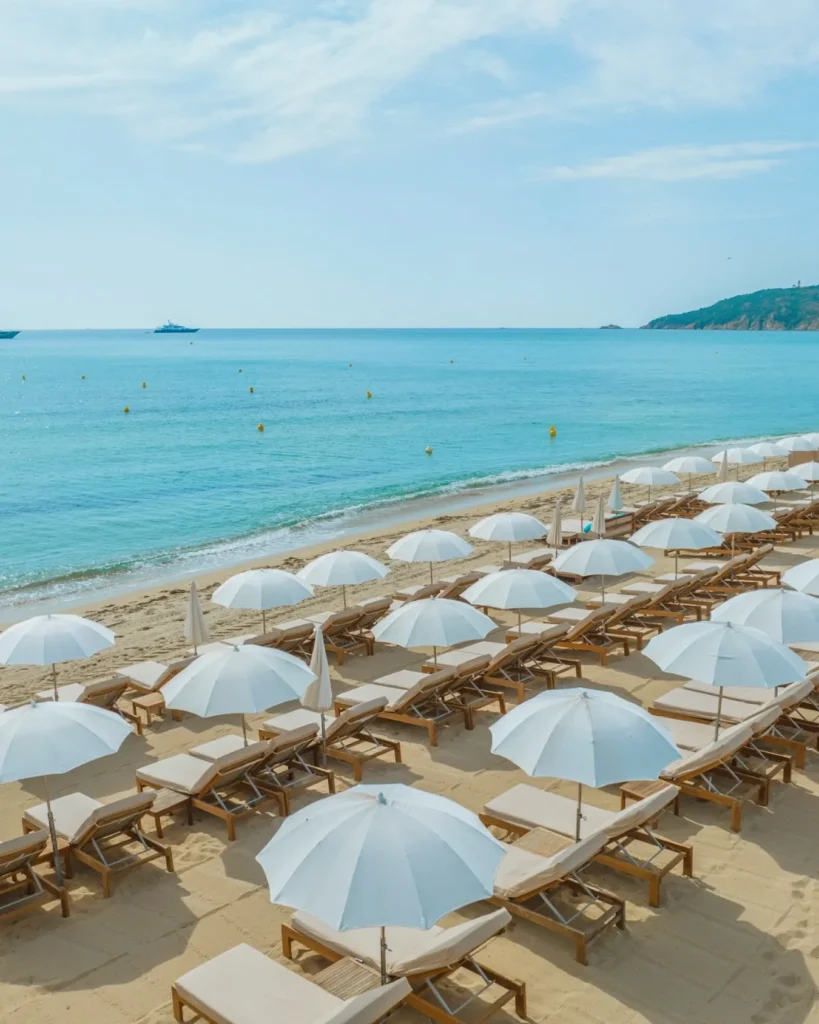 Rows of white parasols and sunbeds facing the turquoise sea at Plage La Serena Ramatuelle Saint-Tropez