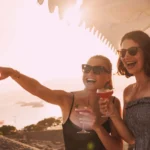Two guests laughing with cocktails at sunset at Plage La Serena Ramatuelle Saint-Tropez