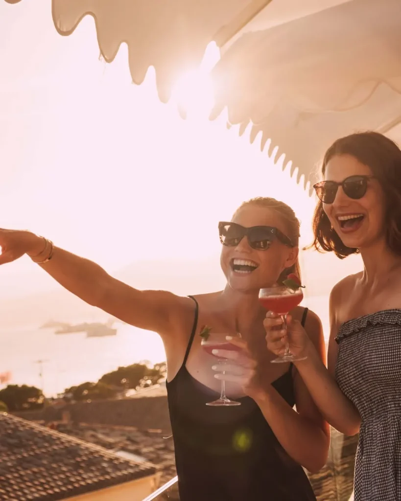Two guests laughing with cocktails at sunset at Plage La Serena Ramatuelle Saint-Tropez