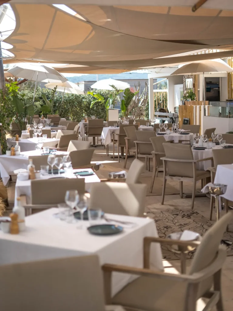 Restaurant tables under sail canopies beside the open kitchen at Plage La Serena Ramatuelle Saint-Tropez