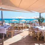 Restaurant deck with parasols opening onto the sea at Plage La Serena Ramatuelle Saint-Tropez