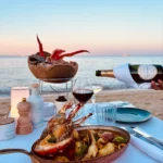 Seafood platter and lobster pan with champagne poured at a beachside table at dusk at Plage La Serena Ramatuelle Saint-Tropez