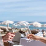 Two guests toasting with white wine over a sea view at Plage La Serena Ramatuelle Saint-Tropez
