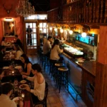 Guests dining beside the tapas bar with a chandelier and mounted antlers at Restaurante El Cuerno Palma