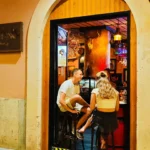 Stone archway looking into the warmly lit bar with guests on stools at Restaurante El Cuerno Palma