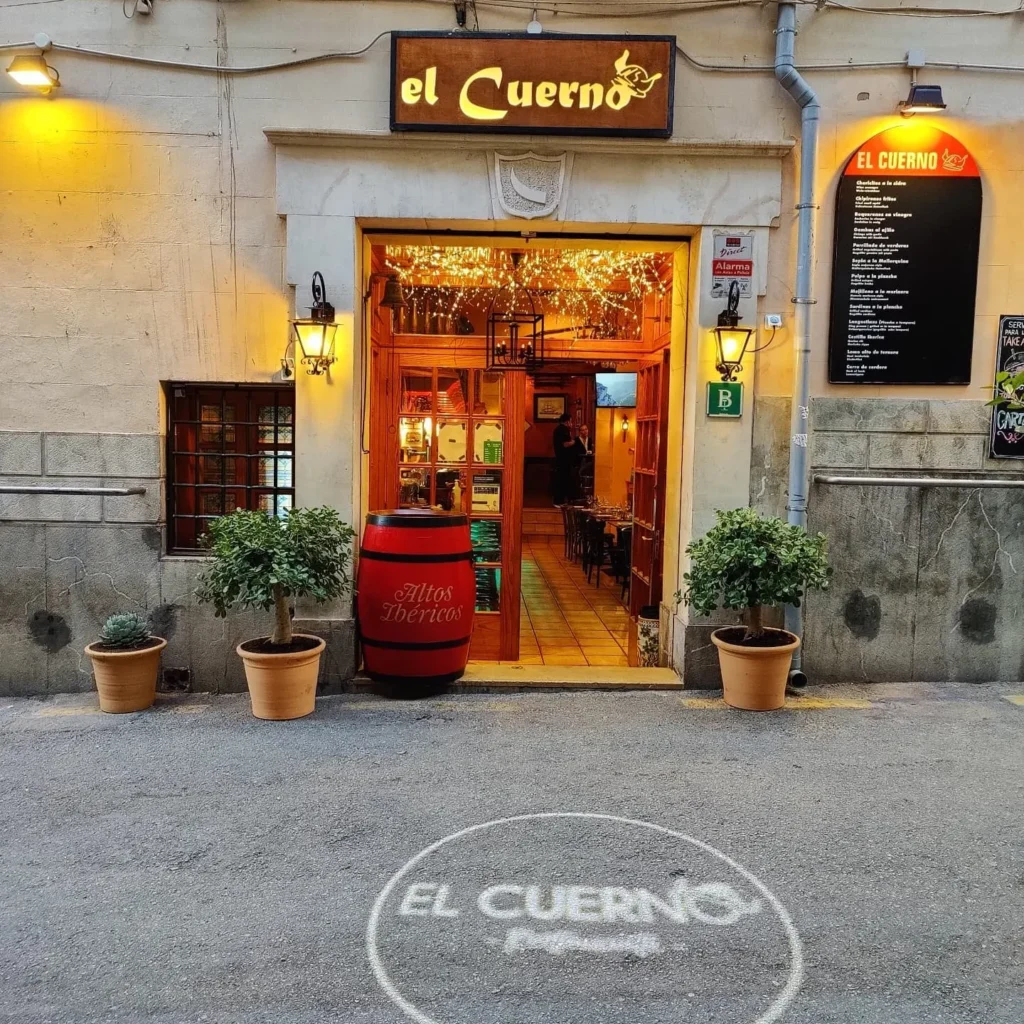 El Cuerno storefront with an illuminated sign, wine barrel and fairy-lit doorway at Restaurante El Cuerno Palma
