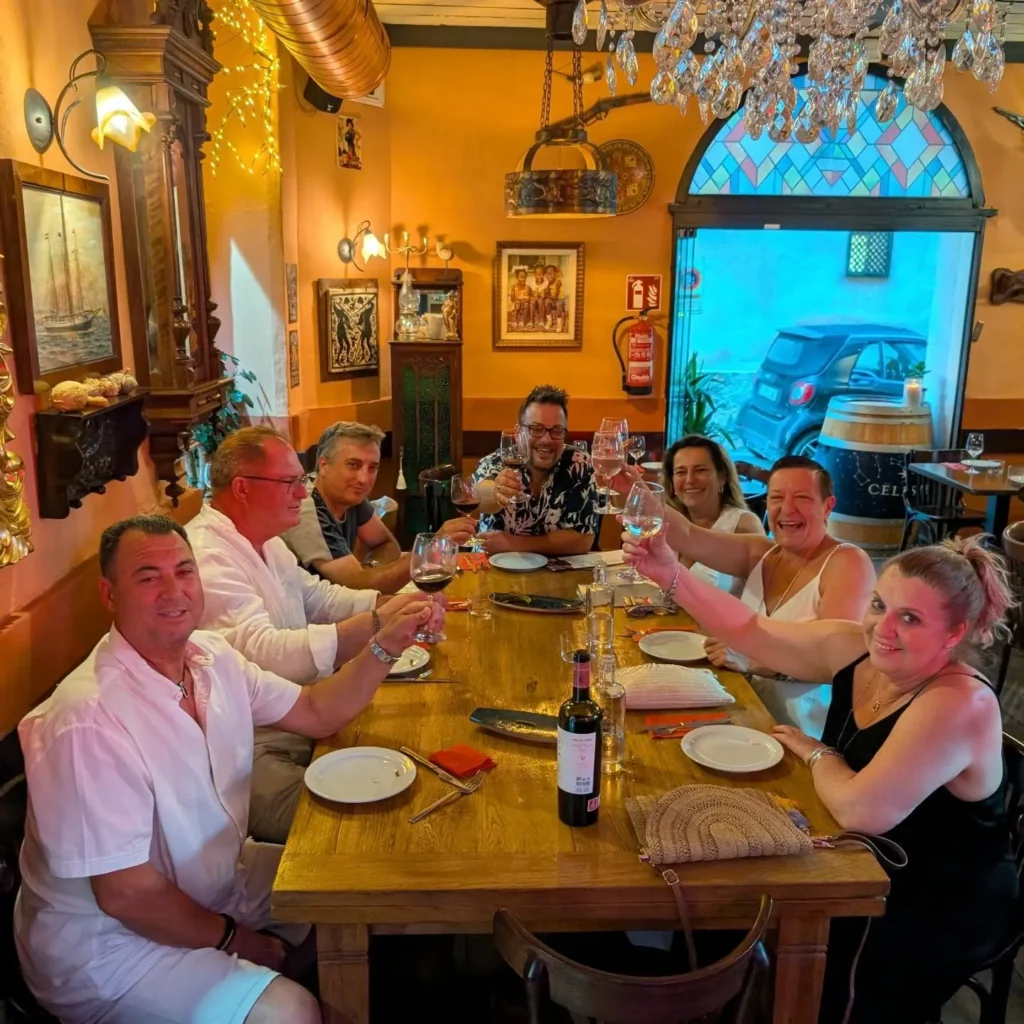 Group of guests raising their glasses around a long table by a stained-glass window at Restaurante El Cuerno Palma