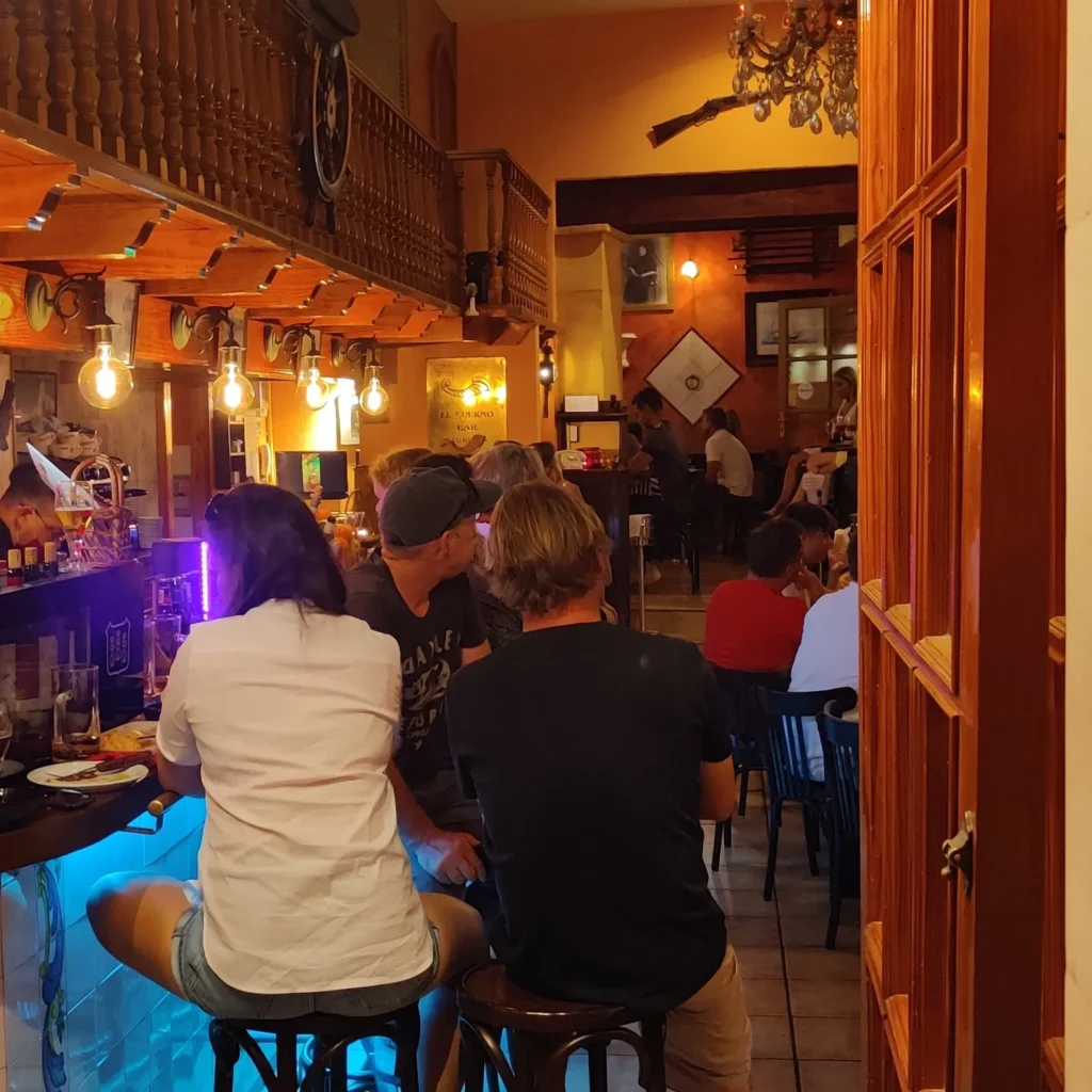 Guests seated at the bar below a wooden mezzanine balustrade at Restaurante El Cuerno Palma