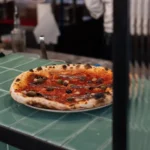 Wood-fired pizza with anchovies and olives at the pass on a green-tiled counter at Rikito Palma