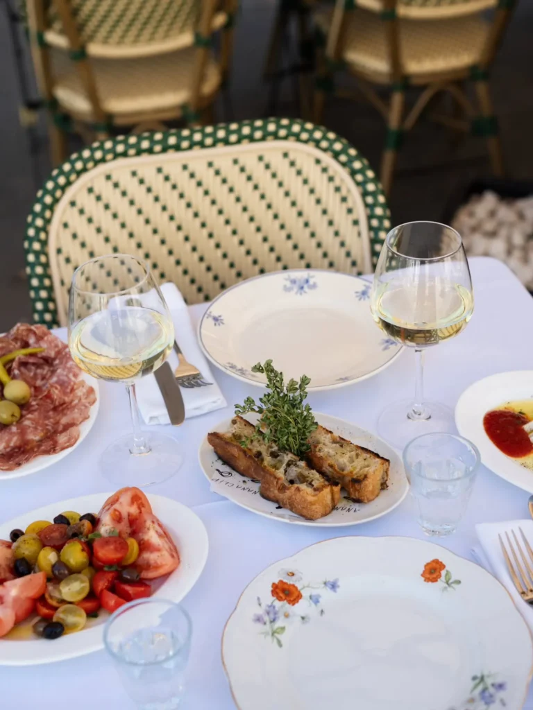 Charcuterie, tomato salad and toasts with white wine on a terrace table at Rikito Palma
