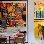 Dining room with a large vintage poster, plate wall and yellow-tiled corner at Rikito Palma