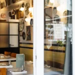 View through the window into the plate-lined dining room with a Rikito menu on the table at Rikito Palma