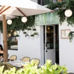 Green-tiled Rikito neon storefront with a shaded terrace and bistro chairs at Rikito Palma