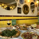 Spread of pizza, courgette carpaccio and cocktails below the plate wall at Rikito Palma