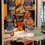 Marble table with a Rikito menu beside a vintage Italian film poster at Rikito Palma