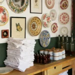 Service station with stacked napkins and pepper mills beneath a wall of decorative plates at Rikito Palma