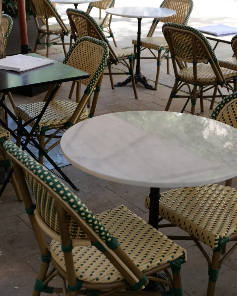 Green-and-cream rattan bistro chairs around marble tables on the terrace at Rikito Palma
