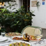 Antipasti and white wine on a terrace table outside the Rikito neon sign at Rikito Palma