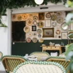 Terrace seating beneath a wall of vintage decorative plates and ivy at Rikito Palma