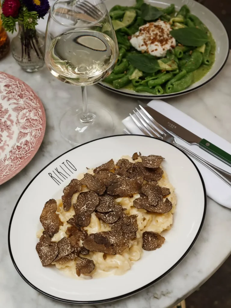 Creamy pasta blanketed in shaved truffle beside a green pasta dish at Rikito Palma