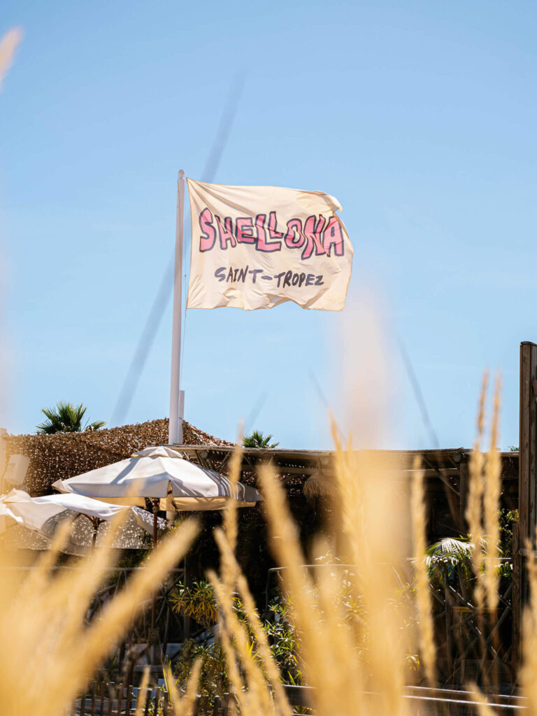 Shellona Saint-Tropez beach club flag flying above the beach club on a sunny day