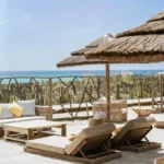 Beachfront lounge with sofas and sunbeds under a thatched umbrella and sea view at Shellona Saint-Tropez