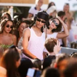 DJ in a headwrap and vest performing amid the crowd at Shellona Saint-Tropez