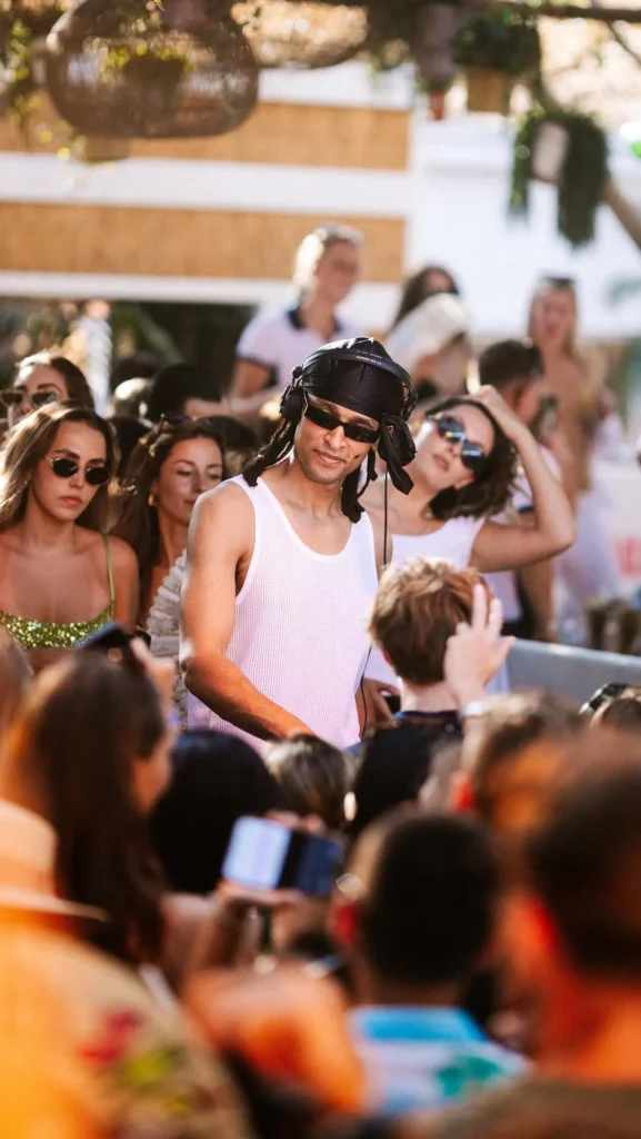DJ in a headwrap and vest performing amid the crowd at Shellona Saint-Tropez