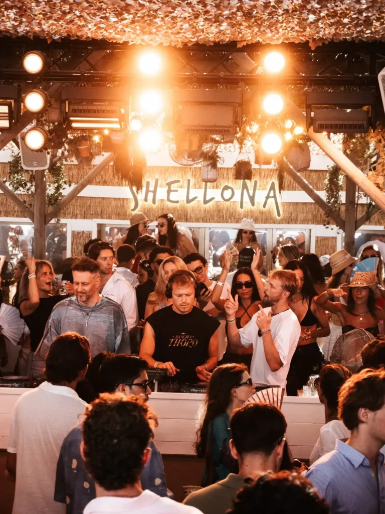 DJ performing to a crowd beneath the lit Shellona sign at Shellona Saint-Tropez