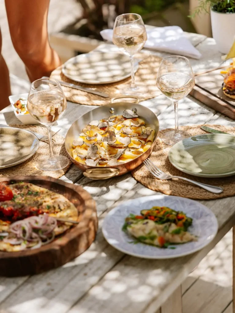 Truffle pasta, grilled fish and sides shared across a wooden table at Shellona Saint-Tropez