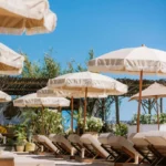 Cream fringed parasols shading sunbeds against a blue sky at Shellona Saint-Tropez