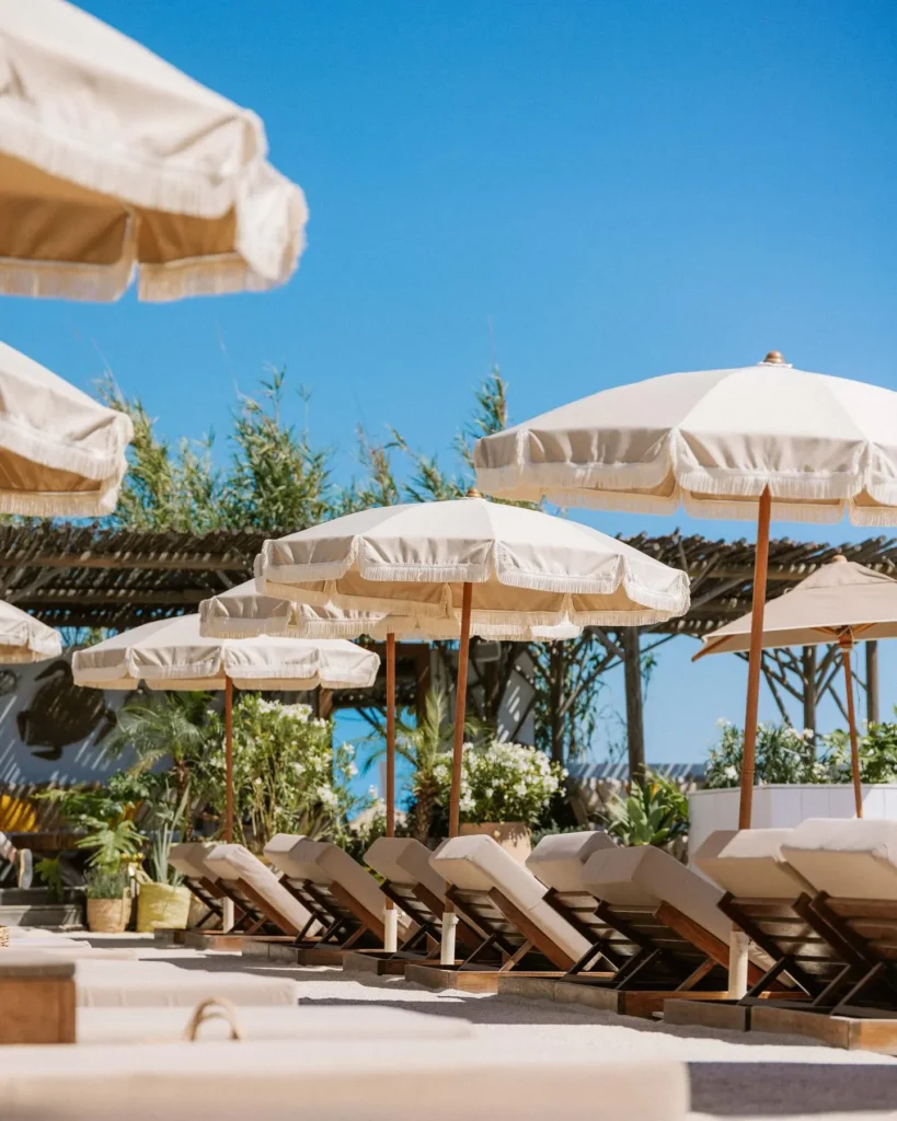 Cream fringed parasols shading sunbeds against a blue sky at Shellona Saint-Tropez