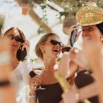 Guests laughing with wine, one in a gold captain's hat, at Shellona Saint-Tropez
