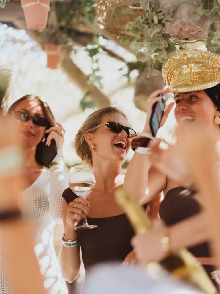 Guests laughing with wine, one in a gold captain's hat, at Shellona Saint-Tropez