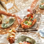 Pizza, tacos and Greek salad shared with white wine on a rustic table at Shellona Saint-Tropez