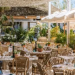 Dining tables and bar among lush plants under a woven canopy at Shellona Saint-Tropez