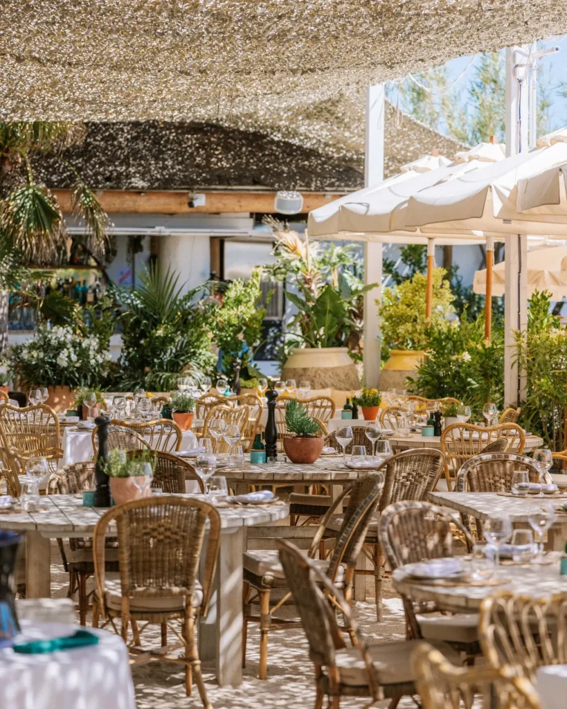 Dining tables and bar among lush plants under a woven canopy at Shellona Saint-Tropez