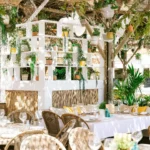 Set tables beside a white shelf of potted plants under a woven pergola at Shellona Saint-Tropez