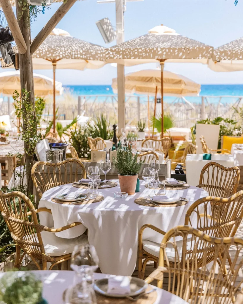 Rattan-chaired tables under parasols framed by greenery at Shellona Saint-Tropez
