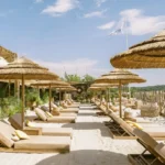 Sandy pathway between sunbeds and thatched umbrellas under the flag at Shellona Saint-Tropez