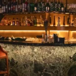 Warmly lit bar area with bottles and glassware at Siena Paris